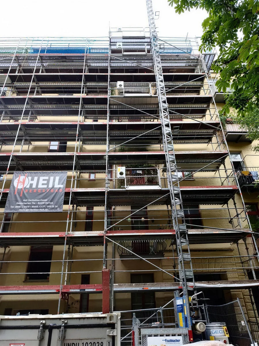 Systemgerüst mit Belägen und Seitenschutz an einer Hausfassade mit Schrägaufzug